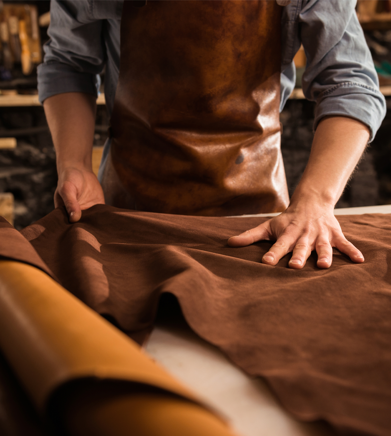 artesano trabajando con pieles en un taller de marroquinería o curtiduría.